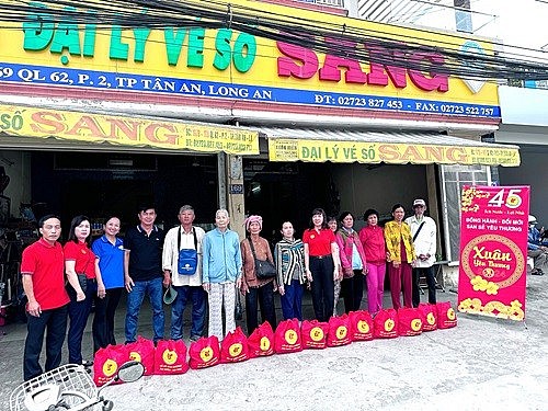 Bà Nguyễn Thị Thu Hằng– Phó giám đốc Công ty (áo đỏ, thứ sáu từ phải qua), ÔngLê Hoàng Trung Tín– PTP Kế hoạch Kinh doanh (thứ nhất từ trái quá) và BàLưu Thị Ánh Nguyệt– Phó Trưởng phòng Trả thưởng (thứ hai từ trái qua) trao tặng quà cho người bán vé số l