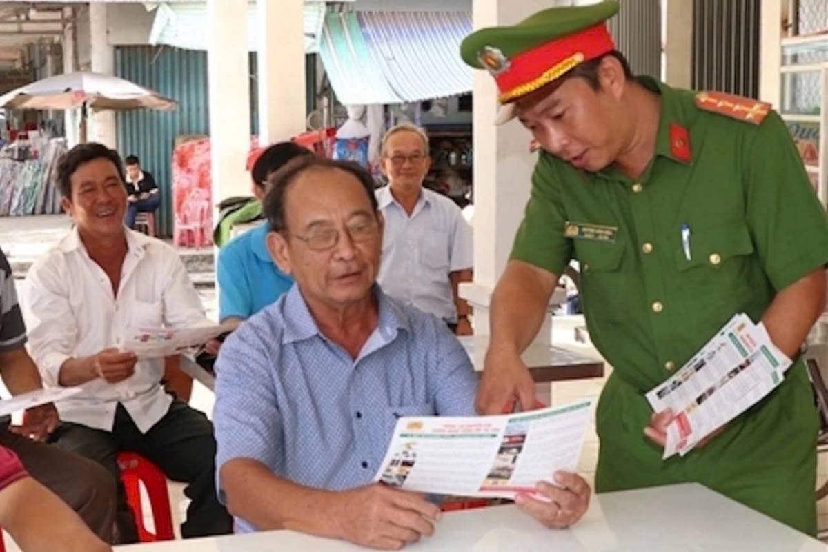 Công an thị trấn Tam Bình (huyện Tam Bình, tỉnh Vĩnh Long) lồng ghép tuyên truyền dịch vụ công và ứng dụng VNeID cho tiểu thương và người dân (Ảnh: CTV).