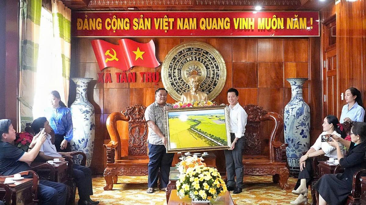 ông Đặng Hoàng Tuấn – Bí thư Đảng ủy xã Tân Trụ (trái) tặng bức tranh kỷ niệm đến đại diện  
