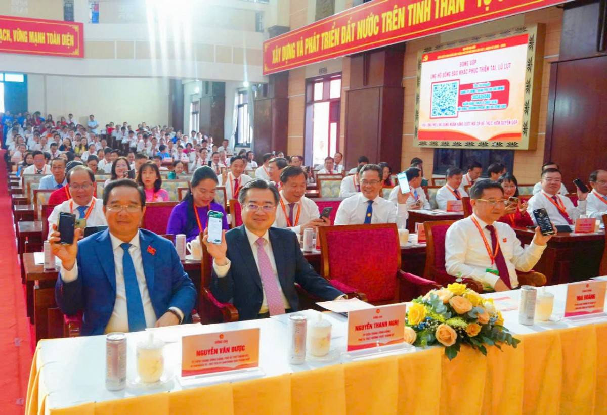 Đại  biểu  thực  hiện  nghi  thức  quyét  mã  QR  ủng  hộ  đồng  bào vùng  thiên  tai