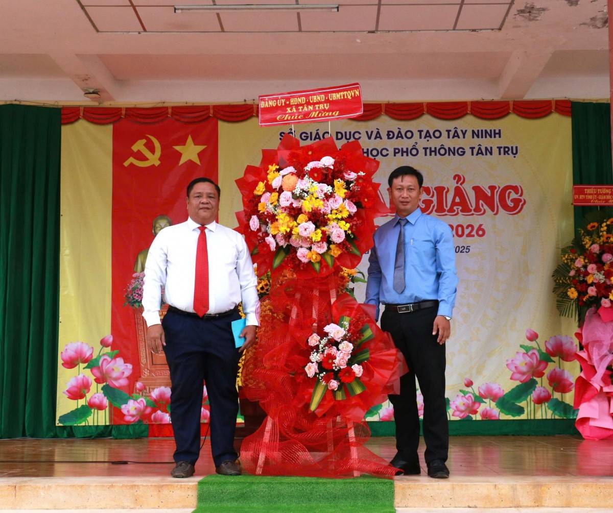 Thay mặt Đảng ủy, HĐND, UBND, UBMT Tổ quốc xã Tân Trụ Tiến sĩ Đặng Hoàng Tuấn – Tỉnh ủy viên, Bí thư Đảng ủy xã tặng hoa . thầy Nguyễn Quang Phúc – Hiệu trưởng nhà trường