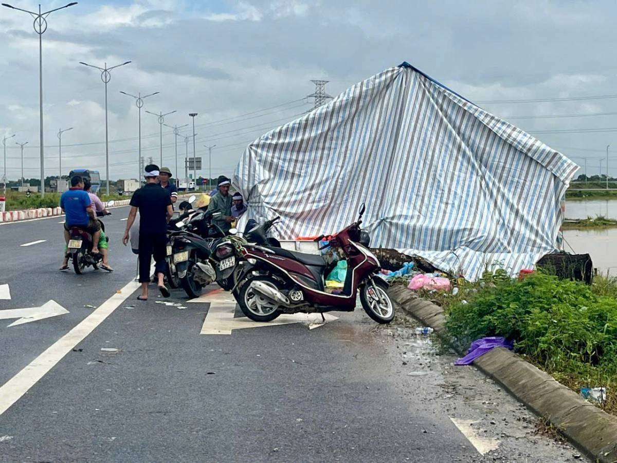 Gia đình dựng lều bạt trên lề đường để tạm quan tài 2 bà cháu, chờ khi nước rút mới có thể trở về.