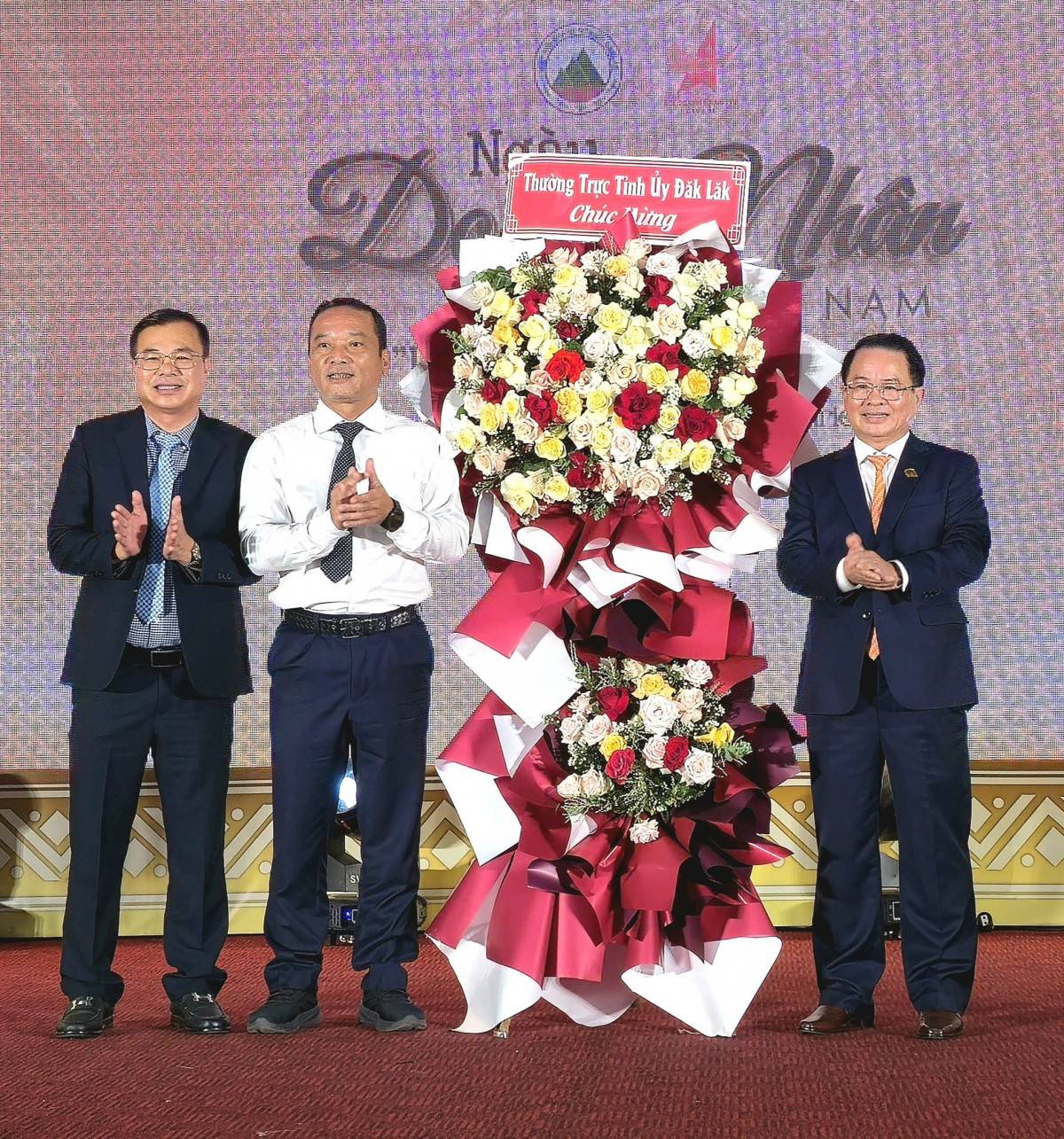 Ông Y Giang Gry Niê KNơng (áo trắng), Phó Bí thư Tỉnh ủy, Chủ tịch Ủy ban MTTQ Việt Nam tỉnh Đắk Lắk tặng lẵng hoa của Thường trực Tỉnh ủy chúc mừng các Doanh nghiệp và doanh nhân nhân Ngày Doanh nhân Việt Nam. 