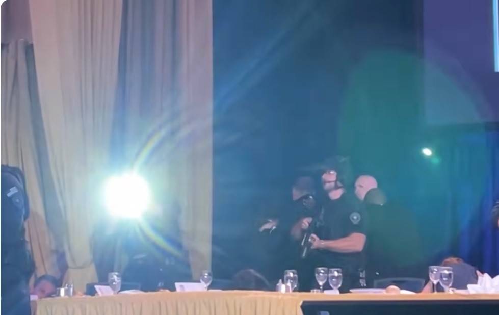 Đặc vụ đứng gần tổng thống sử dụng đèn pin chiến thuật công suất lớn chiếu thẳng xuống đám đông.