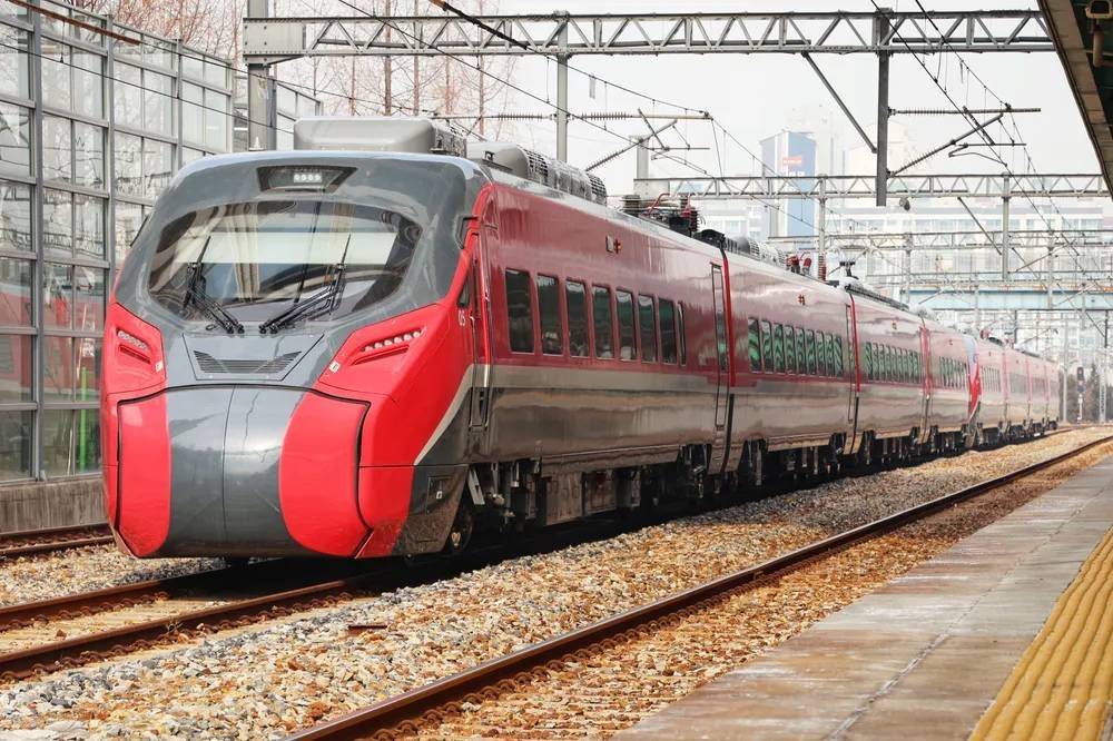 Hàn Quốc có một lịch sử về chính sách công nghiệp chiến lược, bao gồm cả việc chính phủ thúc đẩy sáp nhập ba nhà sản xuất toa xe lửa (Hyundai, Hanjin, Daewoo) thành Tổng công ty Toa xe Hàn Quốc (KOROS), tiền thân của Hyundai Rotem, vào năm 1999 để tránh tình trạng dư thừa công suất và nuôi dưỡng “đầu tàu” quốc gia. 