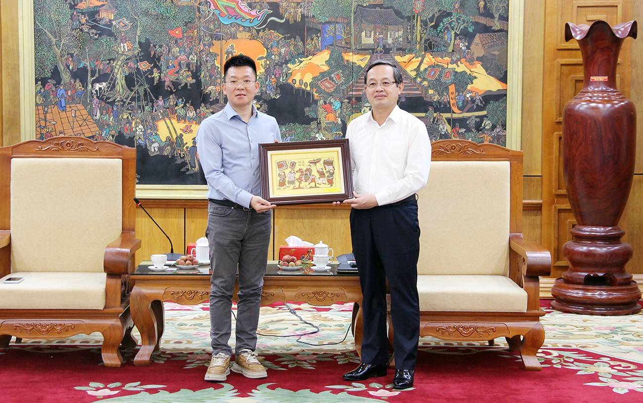 Phó Chủ tịch UBND tỉnh Phạm Văn Thịnh trao tặng bức tranh dân gian Đông Hồ cho ông Richard Zheng, Giám đốc đầu tư Công ty Zhongji Innolight Co., ltd (Trung Quốc).