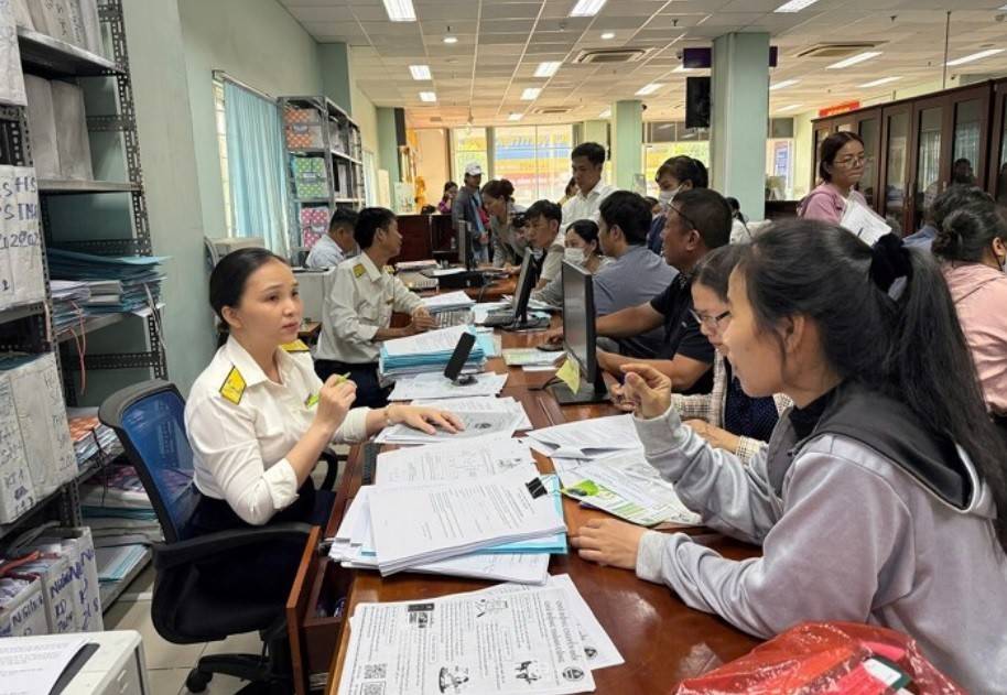 Cán bộ Thuế Cơ sở 12 (thuộc Thuế TP. Hồ Chí Minh) hướng dẫn hộ kinh doanh tháo gỡ các vướng mắc trước khi áp dụng mô hình quản lý thuế mới. (Ảnh: Hứa Chung-TTXVN).