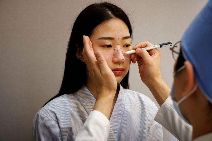 B&amp;aacute;c sĩ tạo d&amp;aacute;ng mũi trước khi phẫu thuật cho một bệnh nh&amp;acirc;n tại bệnh viện thẩm mỹ ở Seoul, H&amp;agrave;n Quốc, hồi th&amp;aacute;ng 12/2020. Ảnh: Reuters.