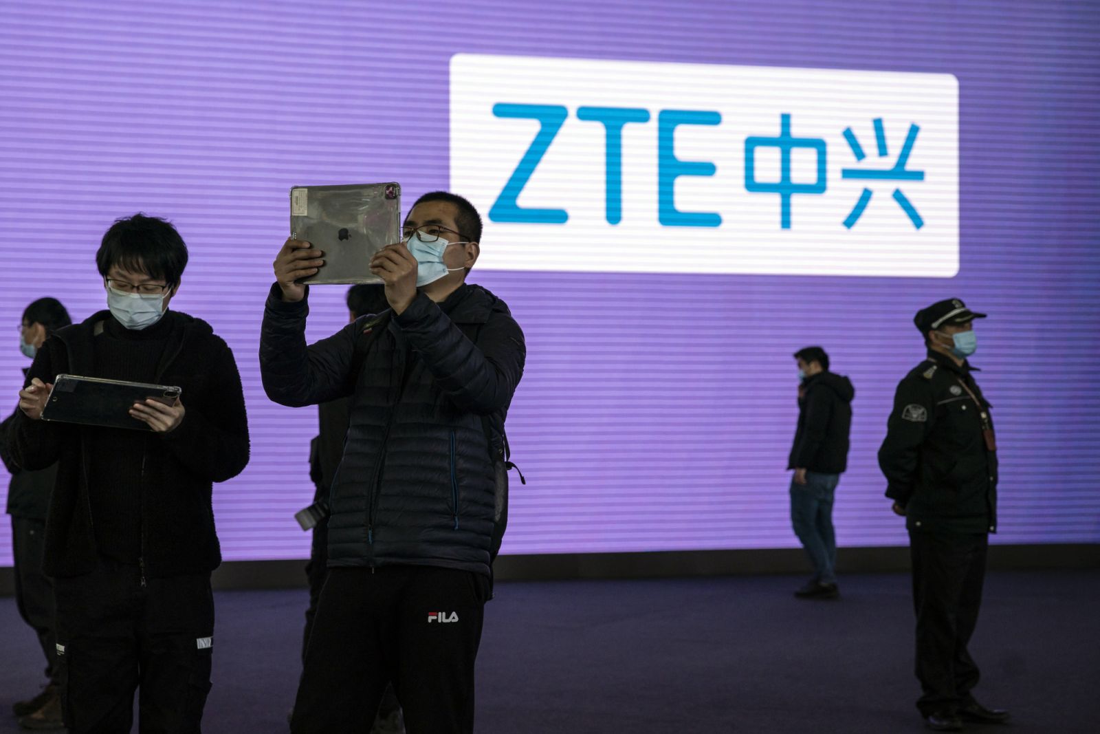 Những người tham dự sử dụng m&amp;aacute;y t&amp;iacute;nh bảng trước biển hiệu của ZTE Corp. tại triển l&amp;atilde;m MWC Thượng Hải ở Thượng Hải, Trung Quốc, v&amp;agrave;o thứ Ba, ng&amp;agrave;y 23 th&amp;aacute;ng 2 năm 2021. Ảnh: Bloomberg