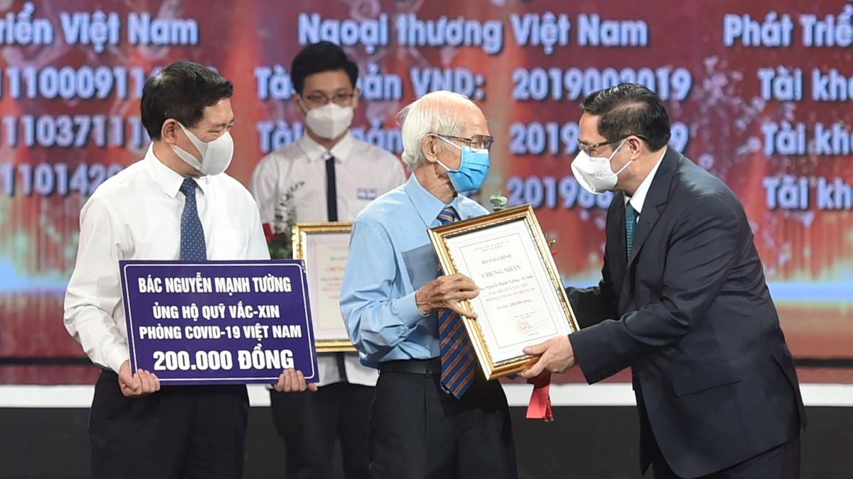 Thủ tướng Ch&amp;iacute;nh phủ Phạm Minh Ch&amp;iacute;nh trao chứng nhận, hoa cảm ơn b&amp;aacute;c Nguyễn Mạnh Tường, 82 tuổi, c&amp;aacute;n bộ hưu tr&amp;iacute; ng&amp;agrave;nh đường sắt tại lễ ra mắt Quỹ vaccine ph&amp;ograve;ng, chống Covid-19.