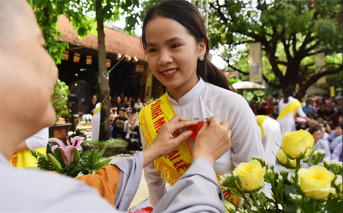 Một nữ sinh được sư thầy ch&amp;ugrave;a Văn Tr&amp;igrave; (H&amp;agrave; Nội) c&amp;agrave;i hoa hồng đỏ l&amp;ecirc;n &amp;aacute;o trong dịp lễ Vu Lan. Ảnh: Giang Huy.