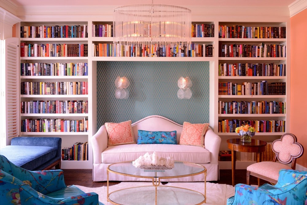 Một ph&amp;ograve;ng kh&amp;aacute;ch chủ đạo l&amp;agrave; m&amp;agrave;u hồng phấn, được t&amp;ocirc; điểm bởi hai chiếc ghế sofa xanh biển tươi tắn v&amp;agrave; rất nhiều s&amp;aacute;ch xếp ngay ngắn tr&amp;ecirc;n kệ.
