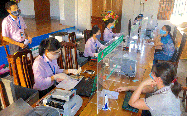 NHCSXH thực hiện giao dịch định kỳ h&amp;agrave;ng th&amp;aacute;ng tại 11.000 Điểm giao dịch tại x&amp;atilde;, phường, thị trấn để giải ng&amp;acirc;n vốn cho người ngh&amp;egrave;o v&amp;agrave; c&amp;aacute;c đối tượng ch&amp;iacute;nh s&amp;aacute;ch kh&amp;aacute;c (Trong ảnh l&amp;agrave; một buổi giao dịch tại x&amp;atilde; Vạn Ninh của NHCSXH tỉnh Quảng B&amp;igrave;nh, c&amp;aacute;c c&amp;aacute;n bộ lu&amp;ocirc;n thực hiện quy định 5K của Bộ Y tế)  Ảnh: Tuấn Ngọc