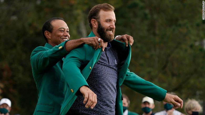 Tiger Woods helps Masters' champion Dustin Johnson with his green jacket after his victory at the Masters golf tournament Sunday, Nov. 15, 2020, in Augusta, Ga.